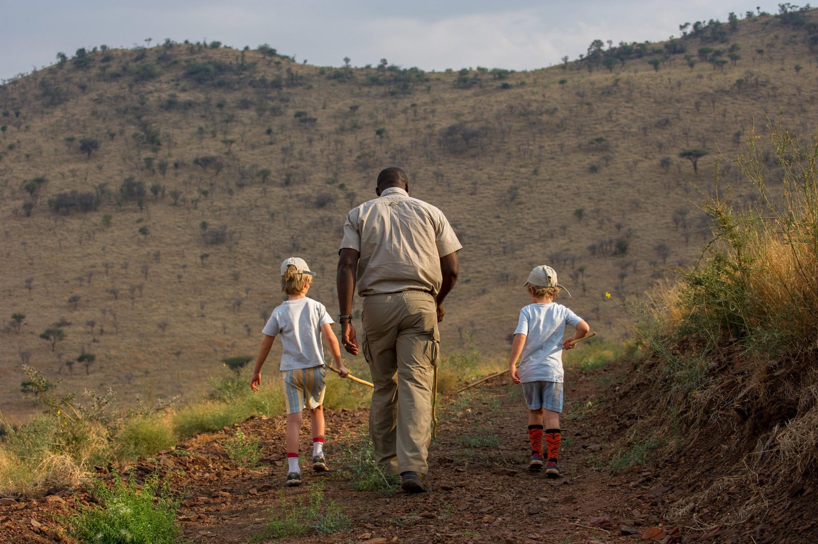 Family walking safari in Tanzania led by a professional guide, with children exploring wildlife safely in a luxury safari setting